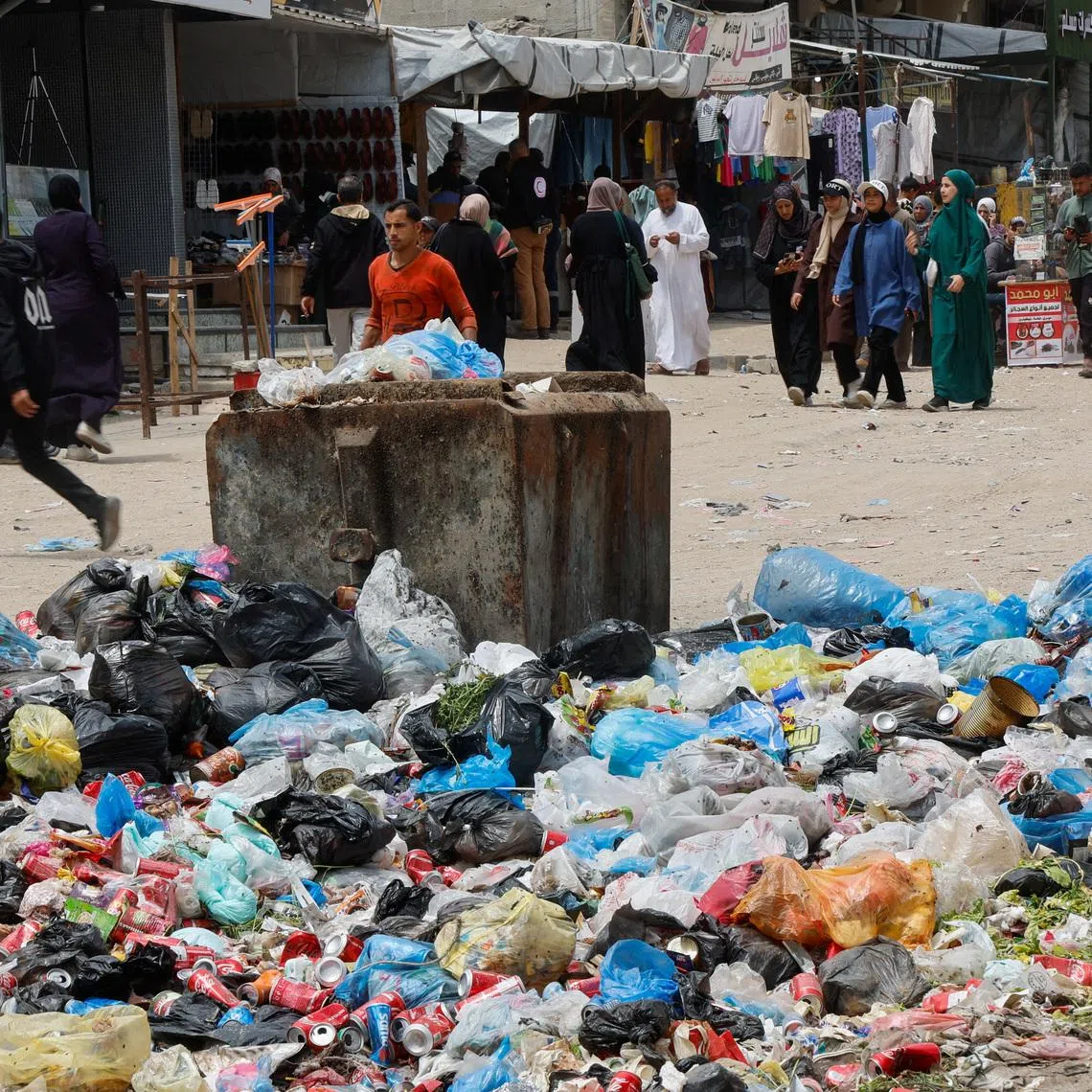 Palestinians walk past piles of garbage and waste near tents for displaced people, amid the spread of rodents, in Khan Younis in the southern Gaza Strip, April 27, 2026. REUTERS/Haseeb Alwazeer