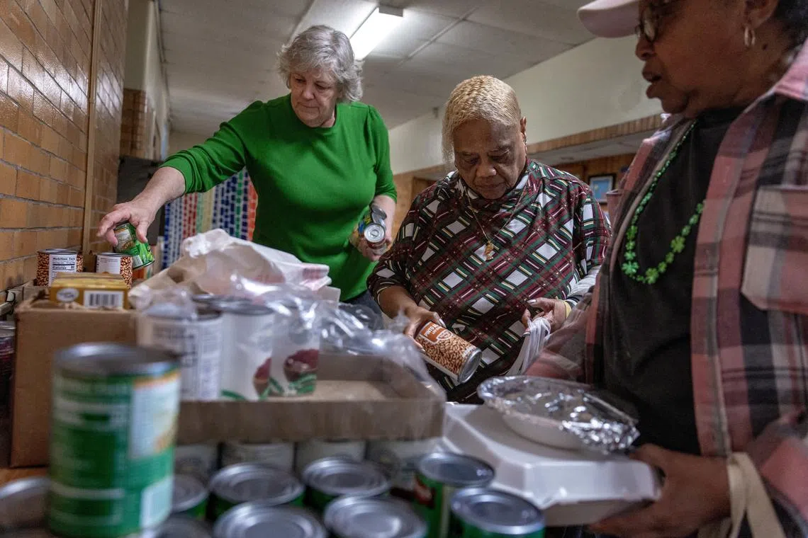 FILE PHOTO: Sara Busse, coordinator for Trinity's Table, a Charleston-based feeding ministry, adds canned goods to a food pantry at the Roosevelt Community Center as food banks across the country, already strained by rising demand, say they will have less food to distribute because of federal funding cuts and pauses by the Trump administration, in Charleston, West Virginia, U.S., March 19, 2025. REUTERS/Evelyn Hockstein/File Photo