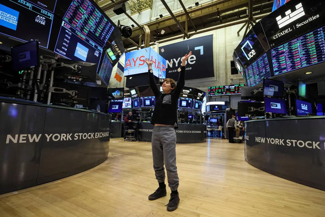 A child of a trader throws ripped paper up during a traditional bring-your-kids-to-work day, on the floor at the New York Stock Exchange.