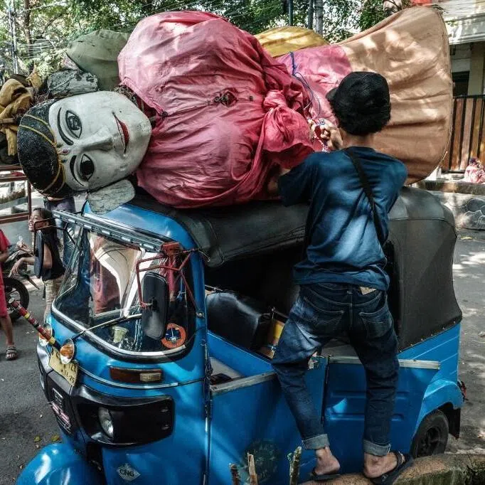 A pair of ondel-ondel puppets are being carried on the roof of a motor tricycle heading to a performance in Jakarta on May 4, 2025. Ondel-ondel are giant traditional puppets from Jakarta's Betawi culture, originally used in rituals and festive parades to ward off evil spirits. 