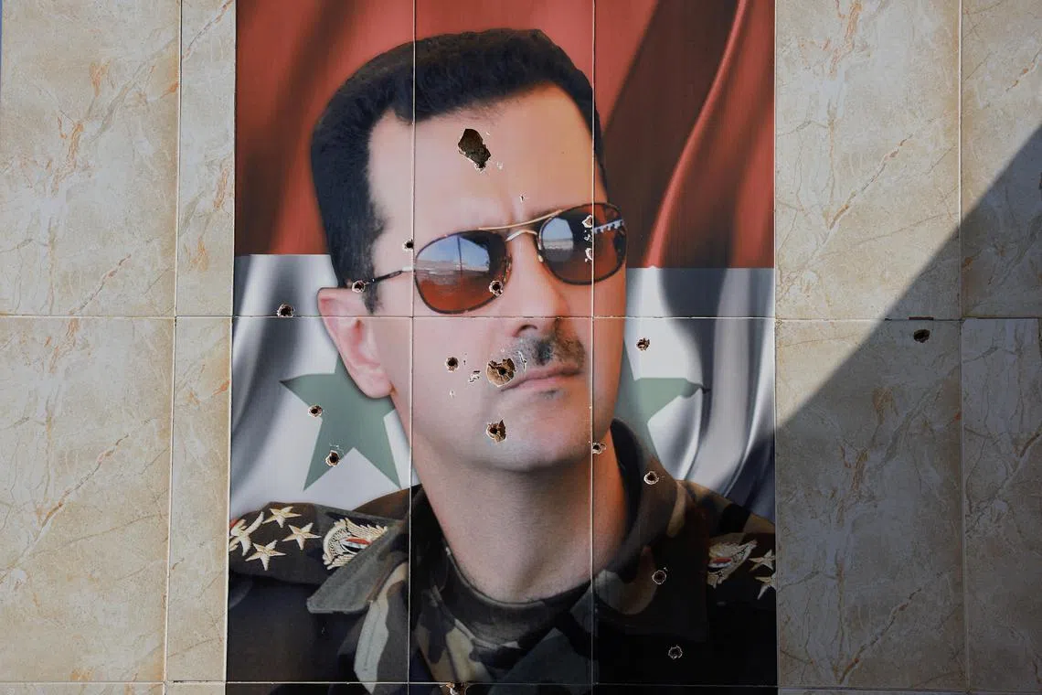 An image of Syria's Bashar al-Assad is damaged by bullet holes, following his ouster.