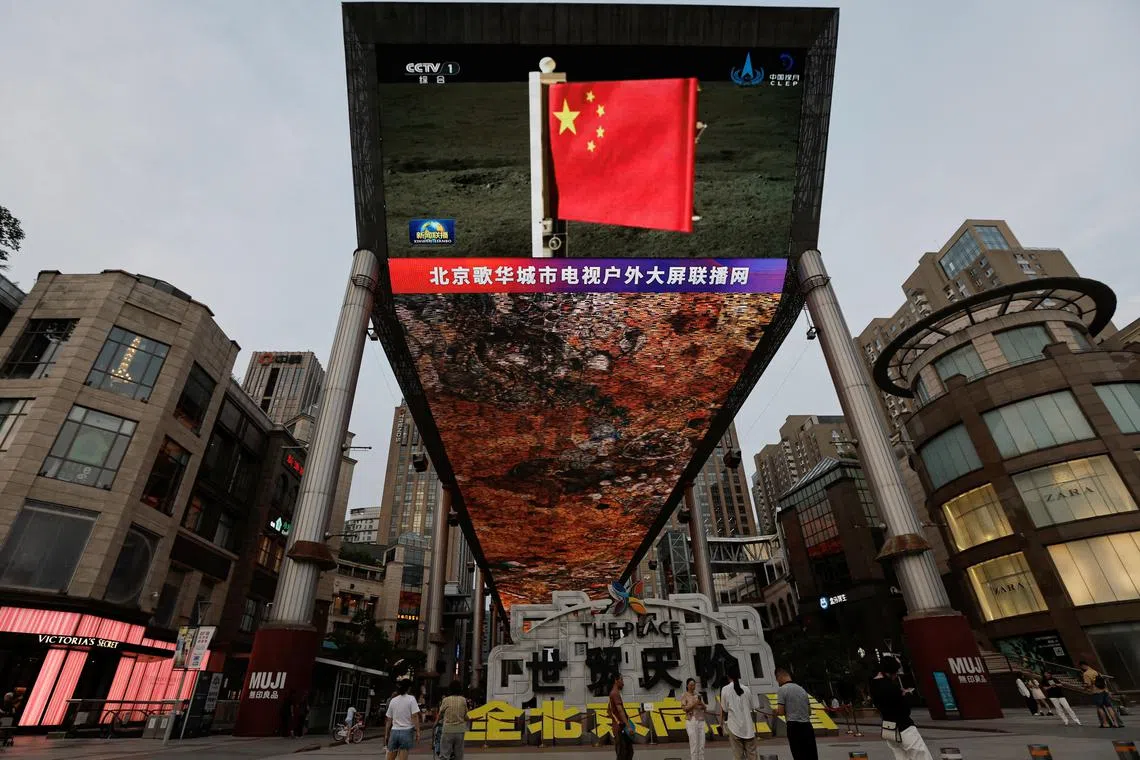 A large screen in Beijing shows news footage of a Chinese national flag carried by Chang'e-6 probe's lander on the far side of the moon, on June 4.