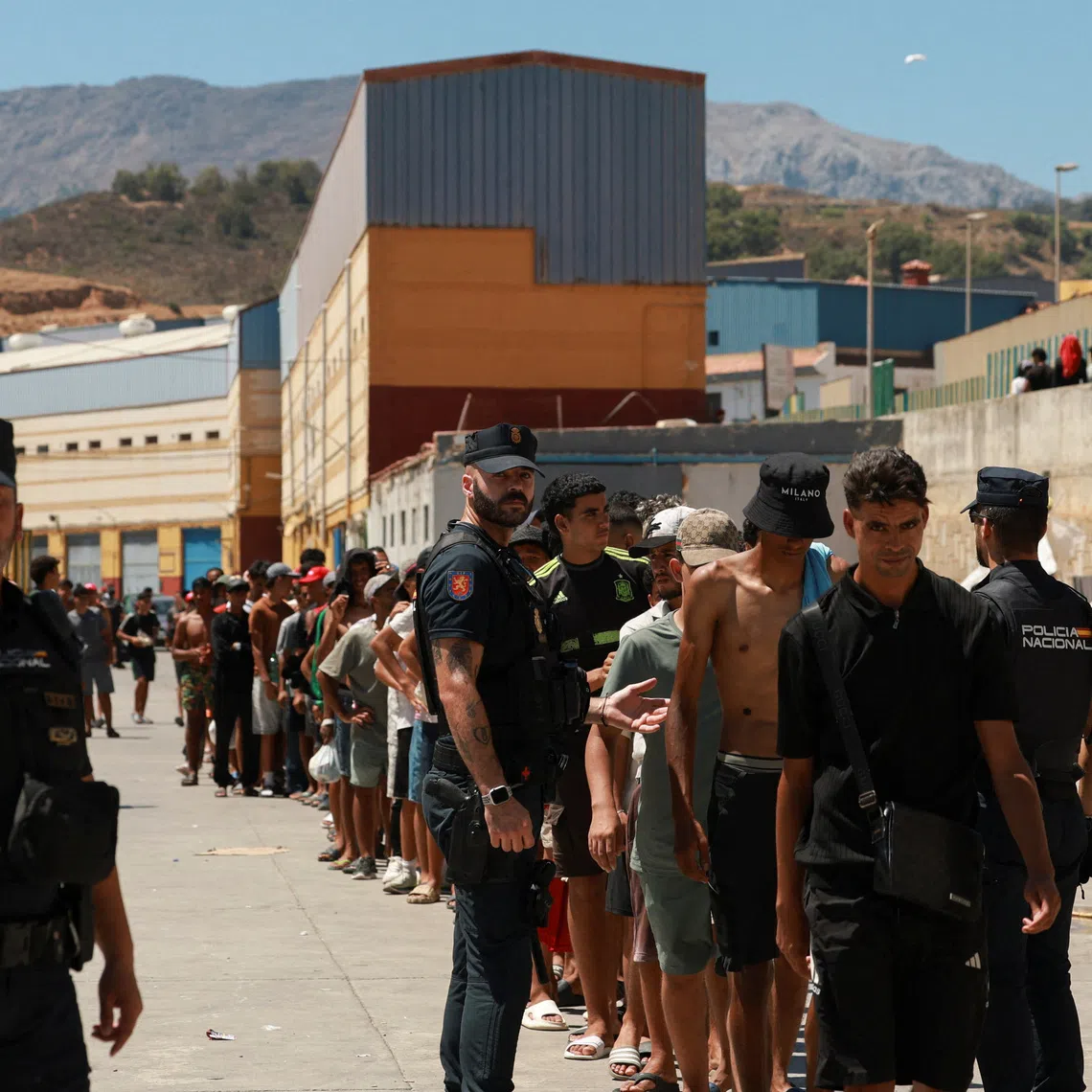 Migrants, some of them minors, queue to receive food staples from local NGO Media Luna Blanca in an industrial area where they are sleeping amid recent mass crossings by migrants on foot and by sea from Morocco into the Spanish territory, in Ceuta, Spain, August 6, 2026. REUTERS/Violeta Santos Moura