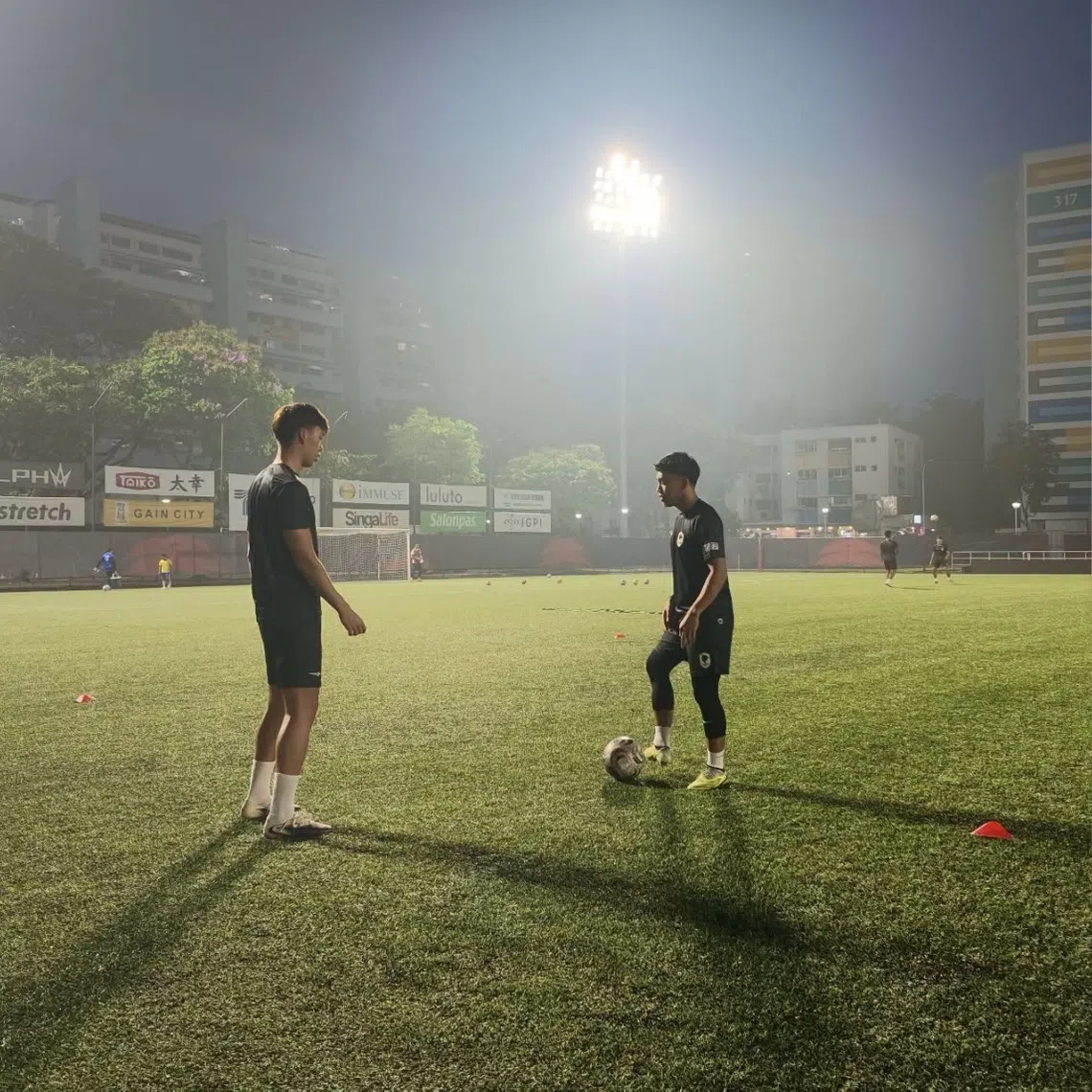 Tanjong Pagar United players Kieran Teo (left) and Syahrul Sazali passing the ball during a training session amid hazy conditions at Jurong East Stadium.