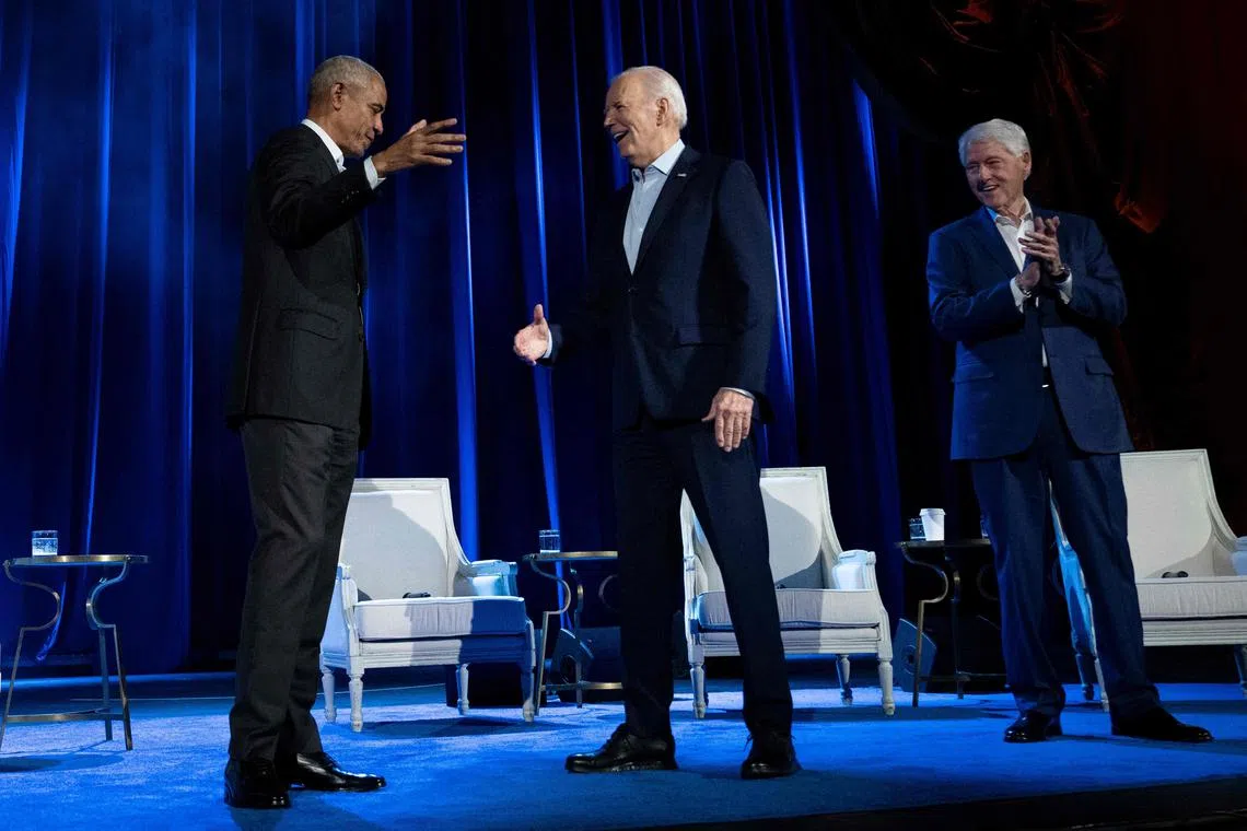 Former US President Bill Clinton (right) watches as former US President Barack Obama (left) and US President Joe Biden shake hands during a campaign fundraising event at Radio City Music Hall in New York City.