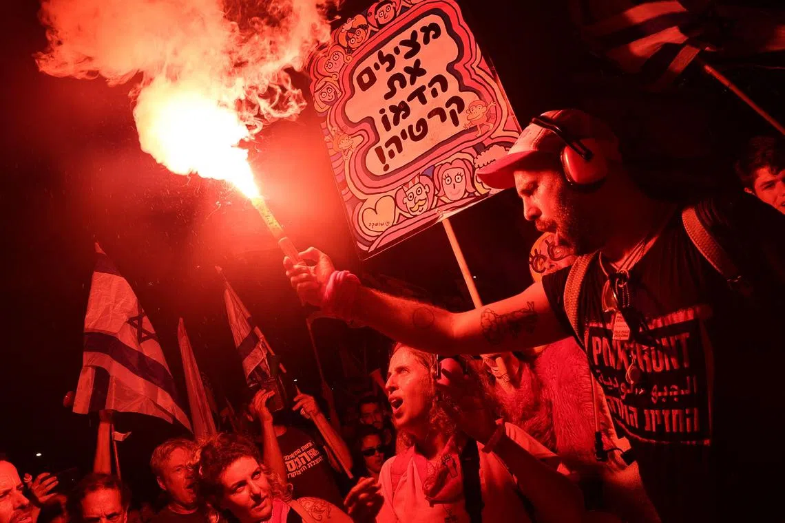 A protester carries a flare during a demonstration against the Israeli government's judicial reform plan in Tel Aviv on July 27, 2023. (Photo by JACK GUEZ / AFP)