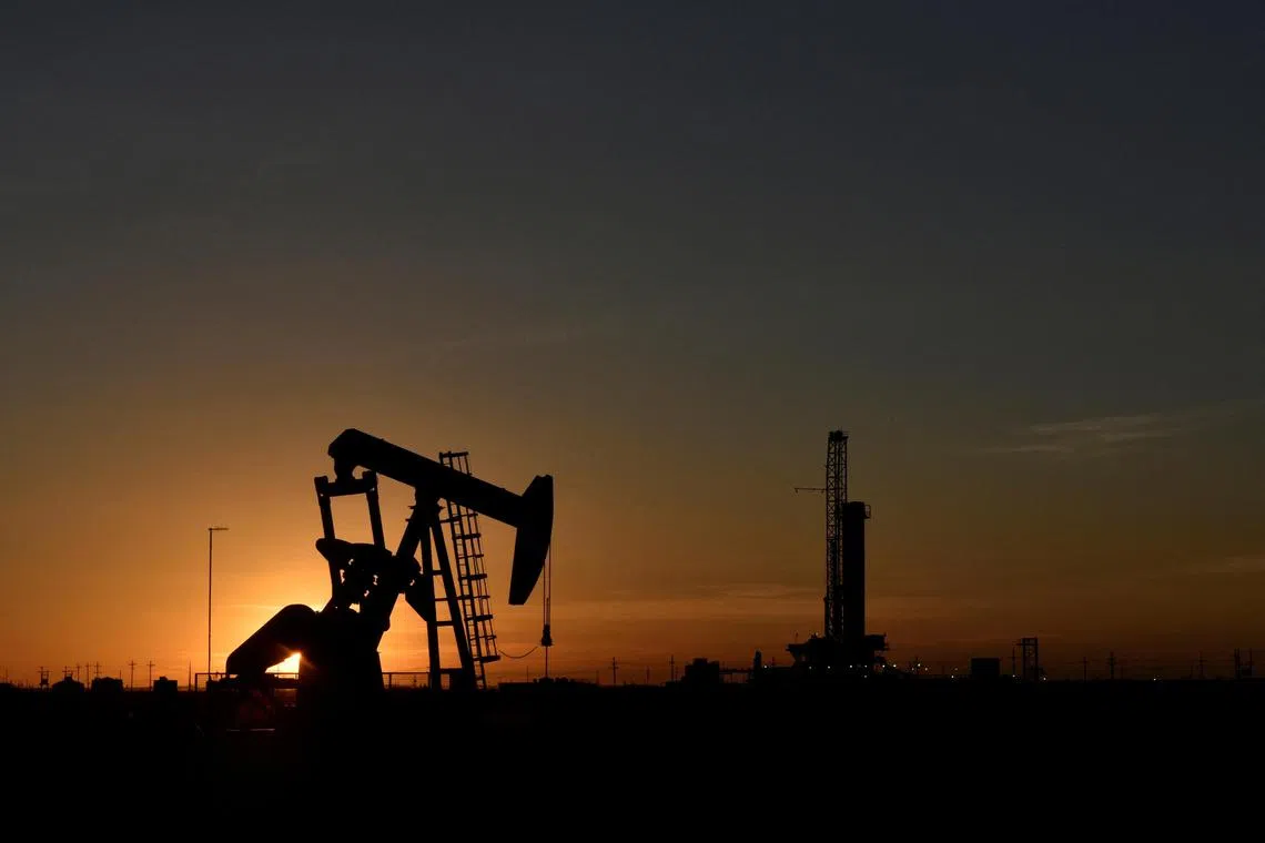 FILE PHOTO: A pump jack operates in front of a drilling rig at sunset in an oilfield in Midland, Texas U.S. August 22, 2018. REUTERS/Nick Oxford/File Photo