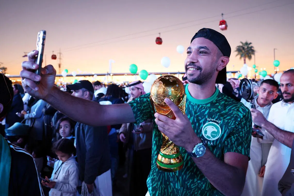 A fan taking a selfie with a replica World Cup trophy as Saudi Arabia is announced as the host nation for the Fifa World Cup 2034.