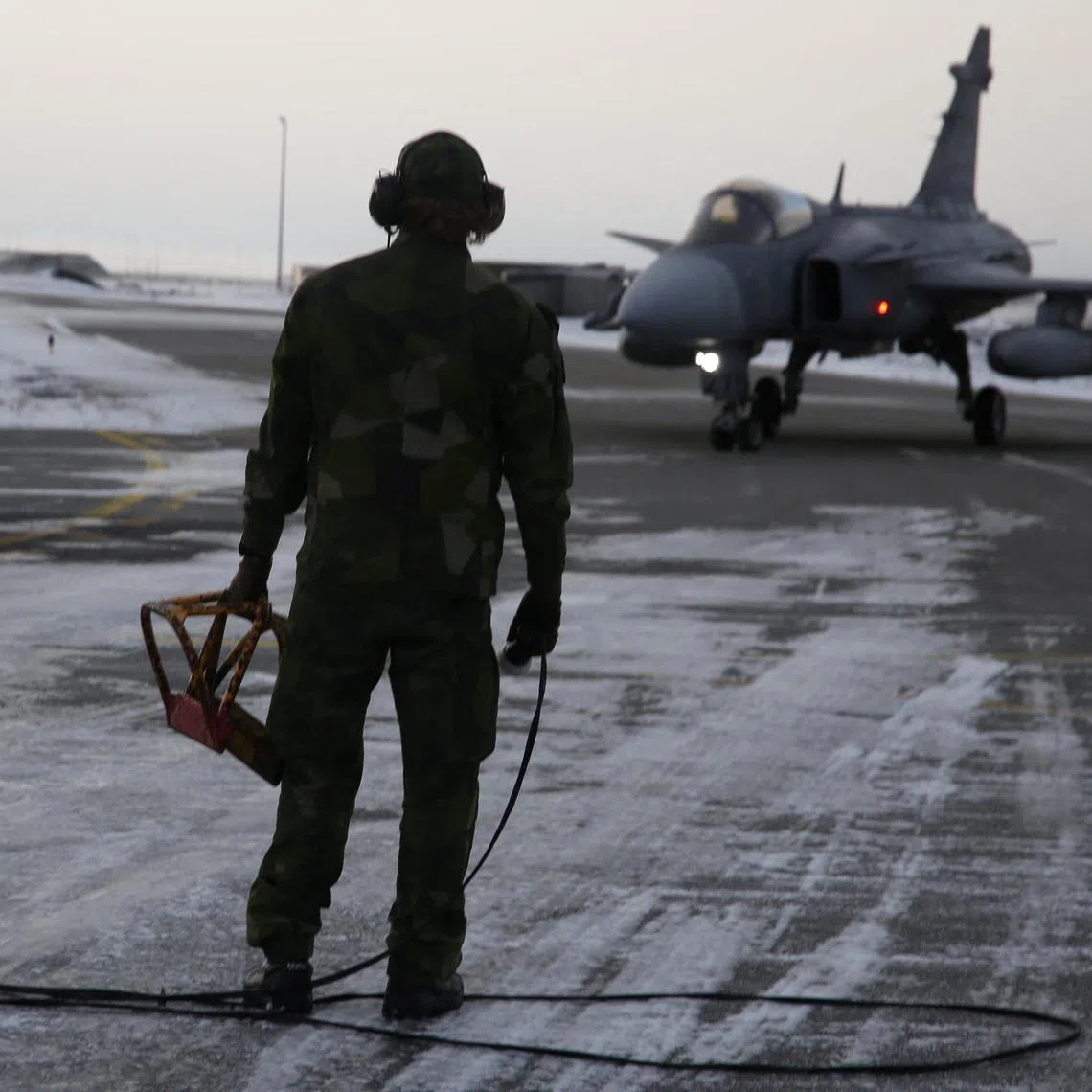 A Swedish ground crew member watches as a JAS 39 Gripen approaches on the tarmac at the air base in Keflavik, Iceland, March 3, 2026. REUTERS/Tom Little