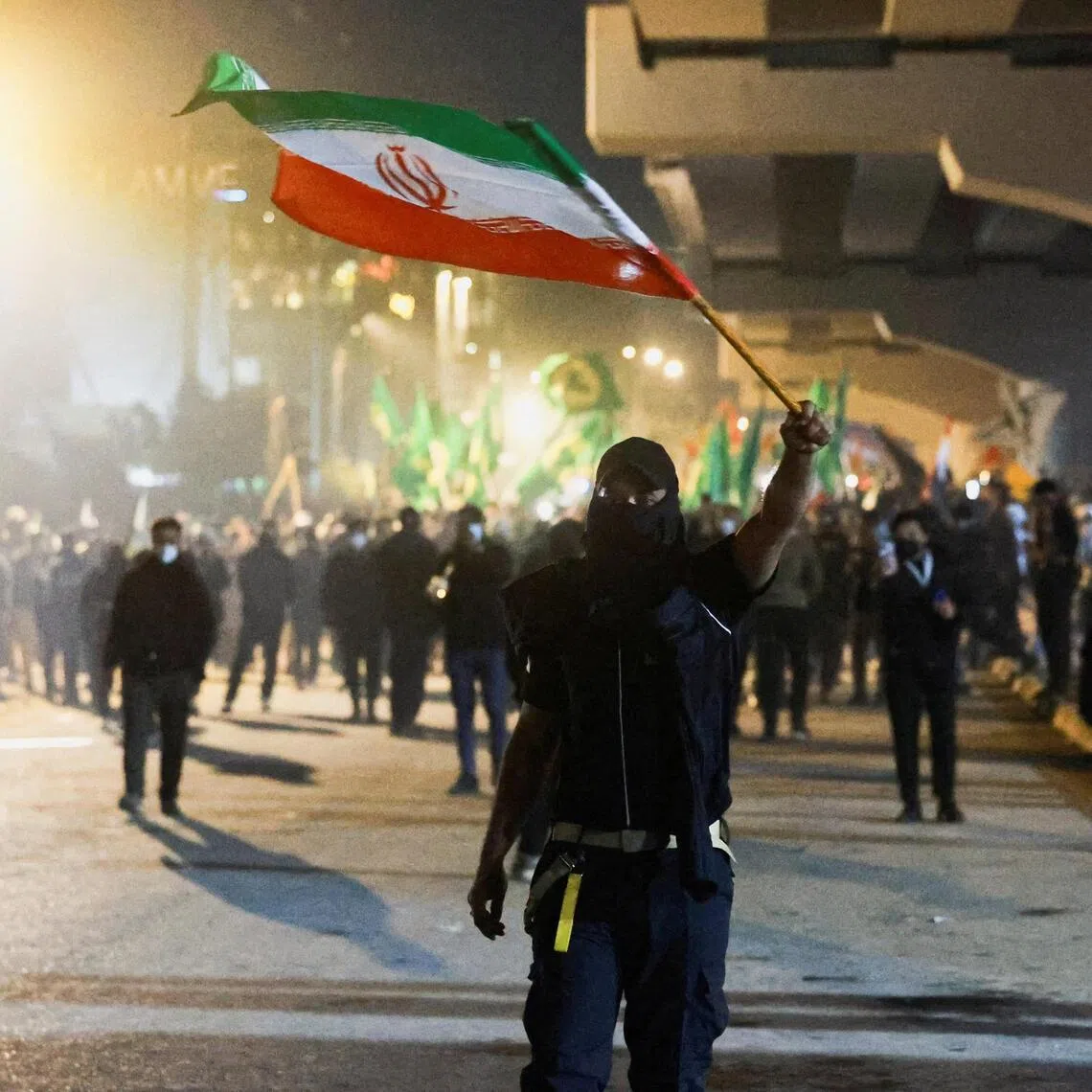 FILE PHOTO: A protester holds an Iranian flag as supporters of Iraqi Shi'ite armed groups attempt to move toward the U.S. embassy located in Baghdad's Green Zone, while riot police deploy to block their advance, following the Israel and U.S. strikes on Iran and the killing of Iran’s Supreme Leader, in Baghdad, Iraq, March 1, 2026. REUTERS/File Photo
