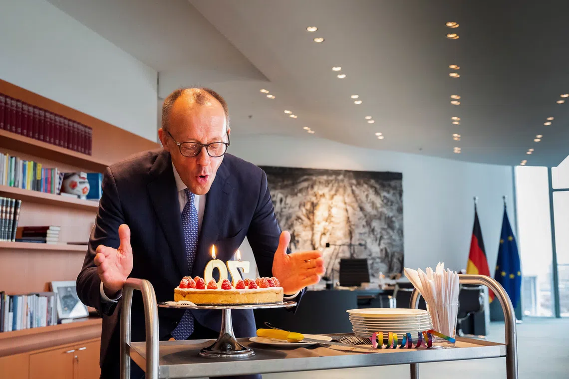 German Chancellor Friedrich Merz blows out some candles on a birthday cake he received by staff of the Chancellery on the occasion of his 70th birthday in Berlin, Germany, November 11, 2025.   Steffen Kugler/BPA/Handout via REUTERS
