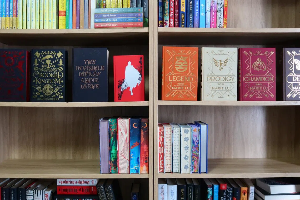 The writer shares some of the special edition books she owns, split into foiled hardcovers on the top shelf and sprayed edges on the bottom shelf.