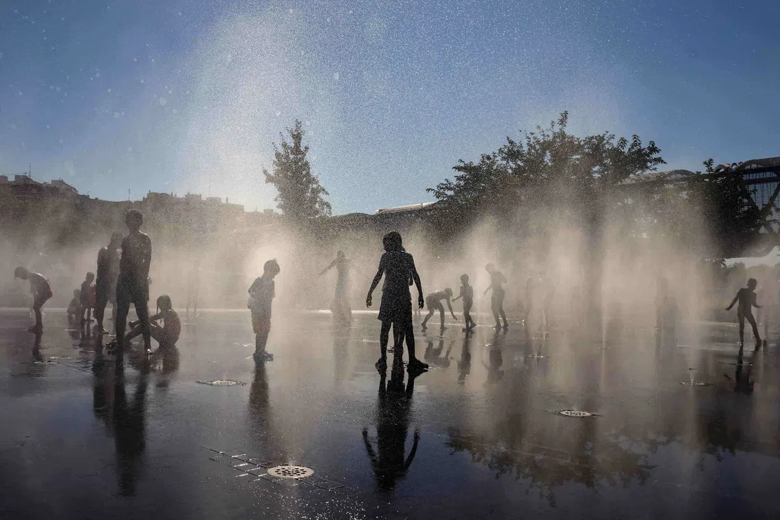 People cooling off at a fountain at Madrid Rio Park amid heatwave conditions in Madrid, Spain, in 2024.