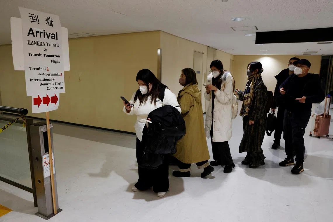 Passengers on a plane from China arrive and head to the coronavirus test area at Narita international airport in Narita, Japan, on Jan 8, 2023. 