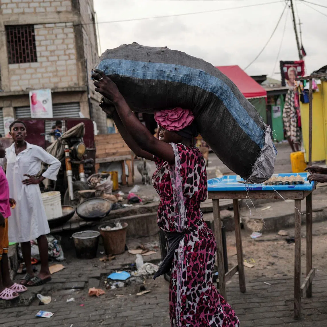 FILE PHOTO: A woman carries sack of charcoal, as she walks down a busy street, in Jamestown in Accra, Ghana  December 6, 2024. REUTERS/Zohra Bensemra/File Photo