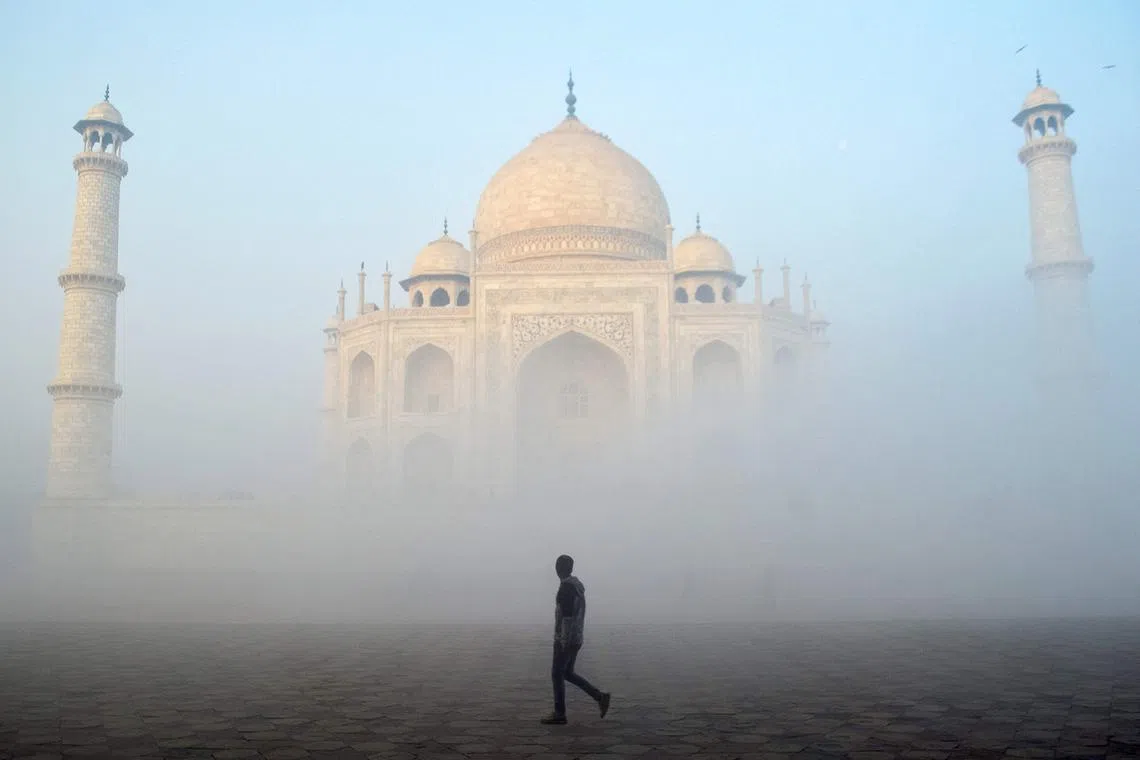 A man walking past the Taj Mahal on a cold foggy morning in Agra, India, on Dec 18, 2024.