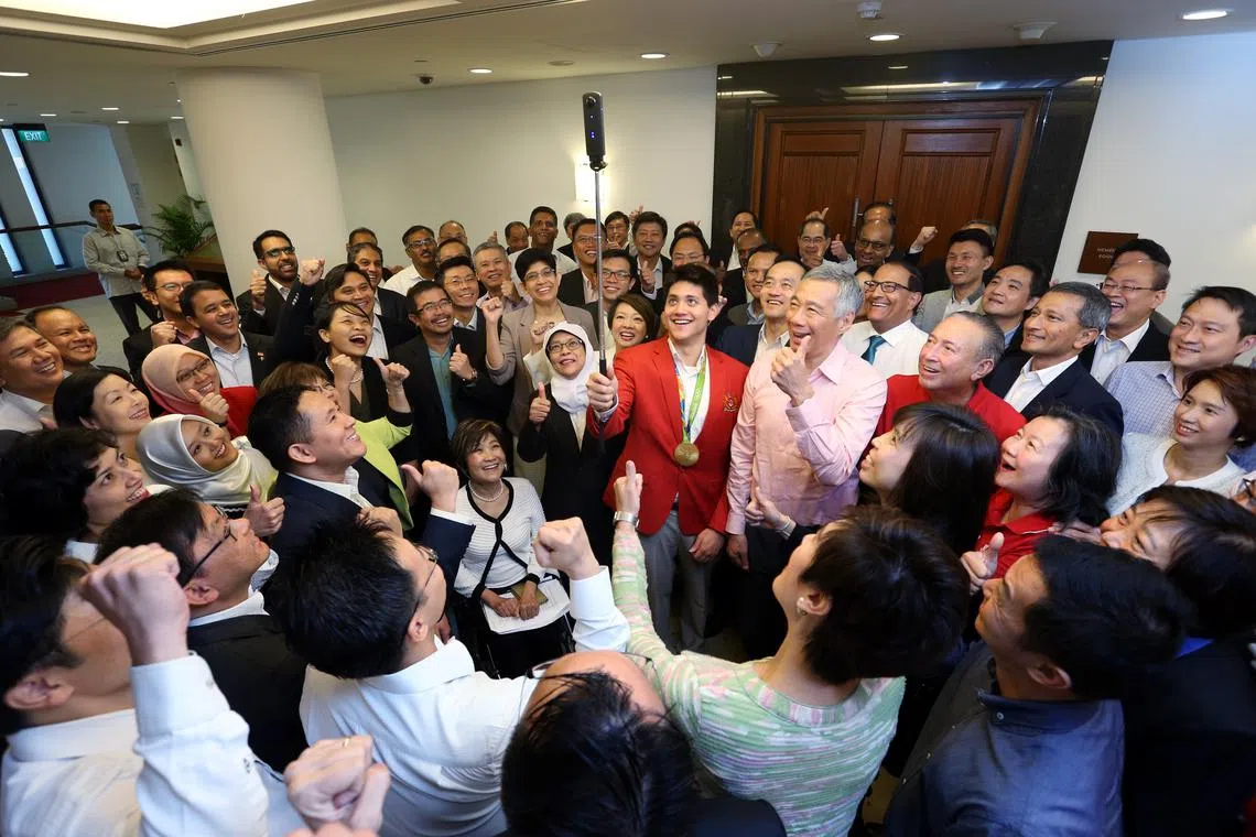 Olympic gold-medalist swimmer Joseph Schooling snapping a photo with Prime Minister Lee Hsien Loong and other MPs on Aug 15, 2016. The Singapore swimmer was formally congratulated for his historic achievement at the Rio 2016 Games during Parliament.