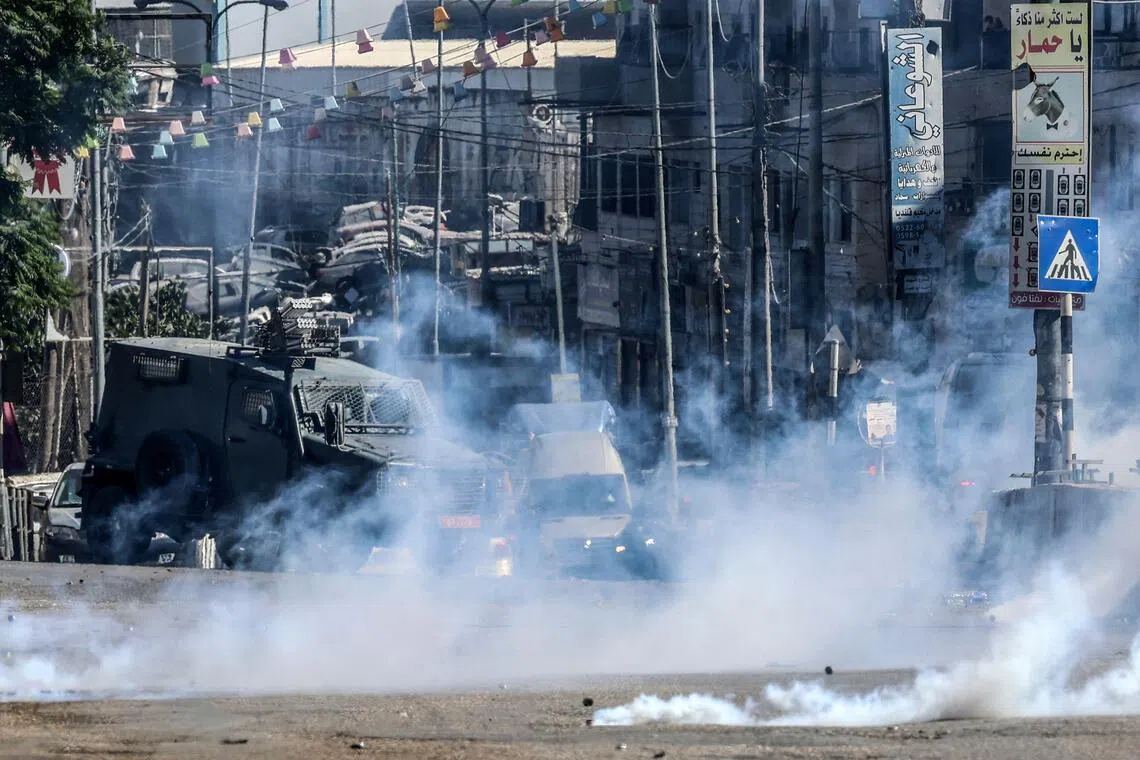 Israeli forces block a street and fire tear gas during an Israeli raid on the UNRWA vocational training centre.