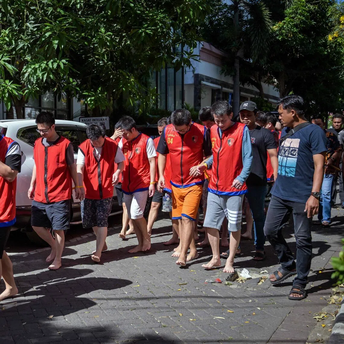 Indonesian police escort a group of online scam suspects from China, Japan and Taiwan.
