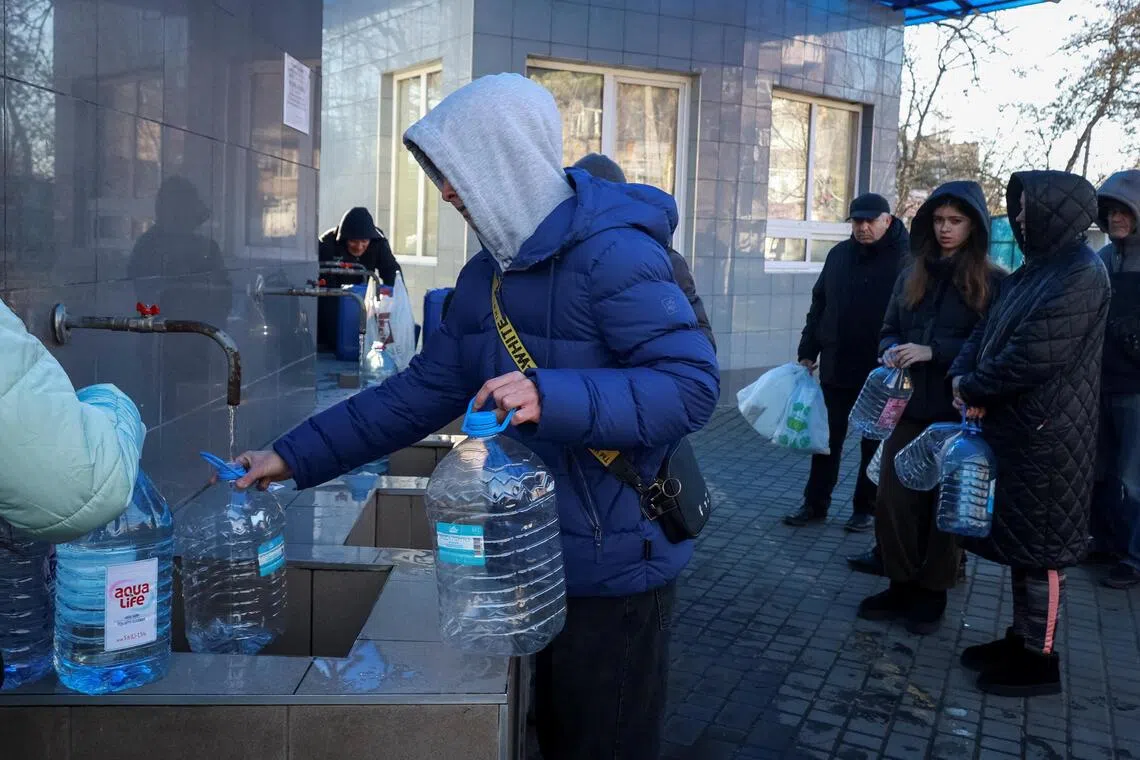 Residents filling up bottles with fresh drinking water, after critical civil infrastructure was hit by Russian missile and drone attacks in Odesa, Ukraine, on Dec 13.