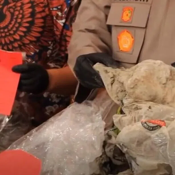 Officers at the Cilacap police station displaying the plastic, cement and sheets the Singaporean victim's body was found in.