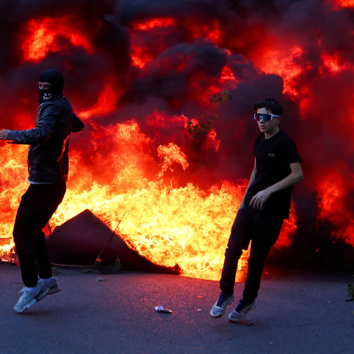 People react near a burning fire, as plumes of black smoke rise, amid an anti-government protest by students, in Tirana, Albania, October 14, 2026. REUTERS/Florion Goga