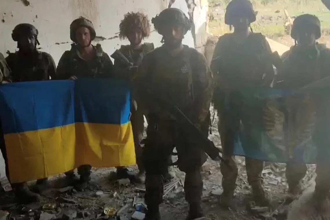 Ukrainian soldiers display Ukraine's flag after recapturing the village of Staromaiorske in their push southward.