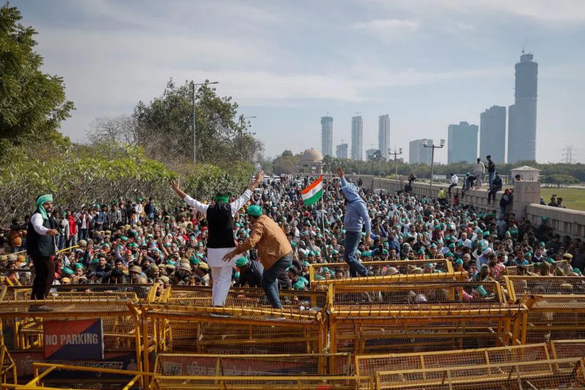 Farmers climb a police barricade during a protest demanding a hike in land compensation and better rehabilitation facilities for their families, in Noida on the outskirts of New Delhi, India, February 8, 2024. REUTERS/Adnan Abidi/File Photo