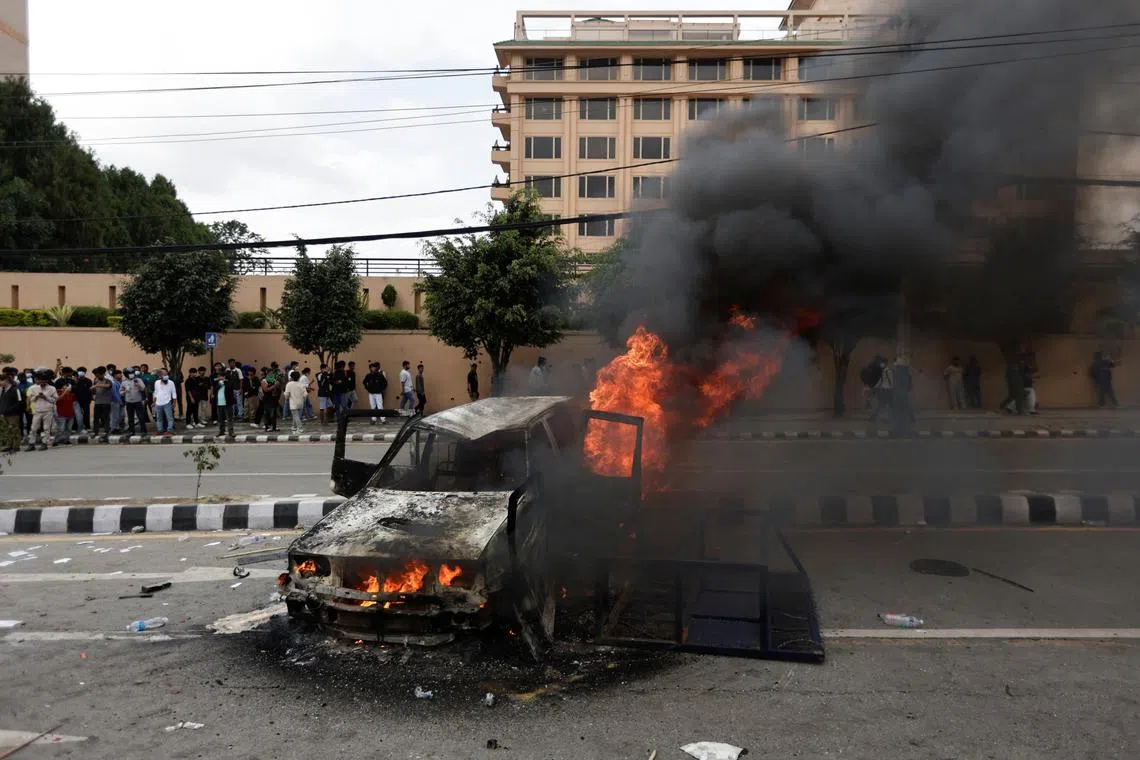 People stand near a vehicle torched by the demonstrators during a protest against corruption and the government’s decision to block several social media platforms, in Kathmandu, Nepal, September 8, 2025. REUTERS/Navesh Chitrakar