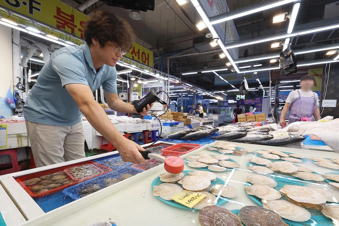 A shopkeeper measures radiation levels of scallops from Japan at a fishery market in Daegu, South Korea.