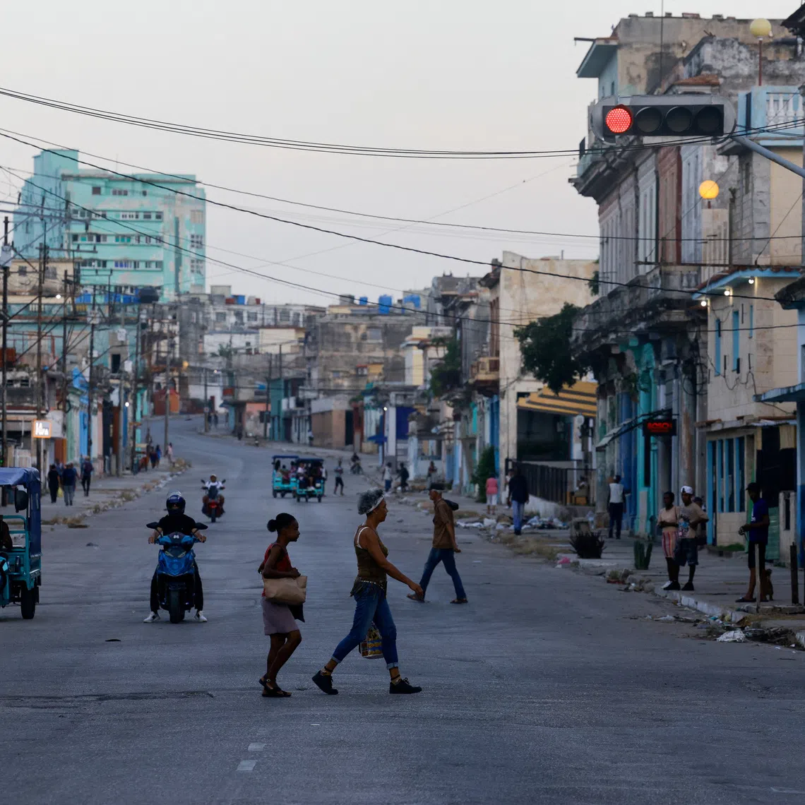 People cross a street as Cuba's national power grid is restored following its collapse, which marked the third major outage in nine days, in Havana, Cuba, July 15, 2026. REUTERS/Norlys Perez