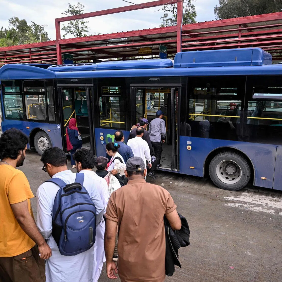 Passengers queue to board a government bus at a bus stop in Islamabad on April 3, 2026. State-run public transport in Pakistan's capital and most populous province will be free for the coming month, officials said on April 3, after the government drastically raised fuel prices due to spiking global energy prices caused by the Iran war. (Photo by Farooq NAEEM / AFP)
