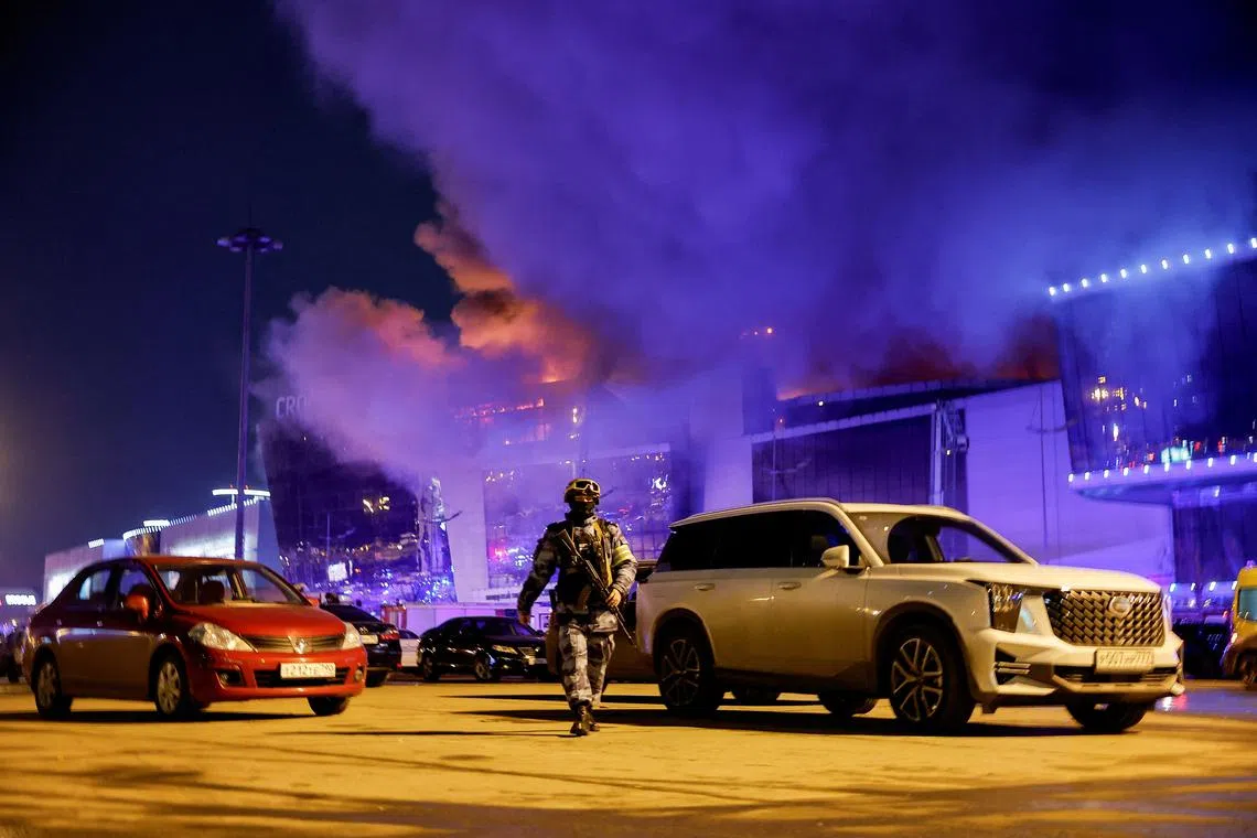 A Russian law enforcement officer walks at a parking area near the burning Crocus City Hall concert venue following a shooting incident, outside Moscow, Russia, March 22, 2024. REUTERS/Maxim Shemetov