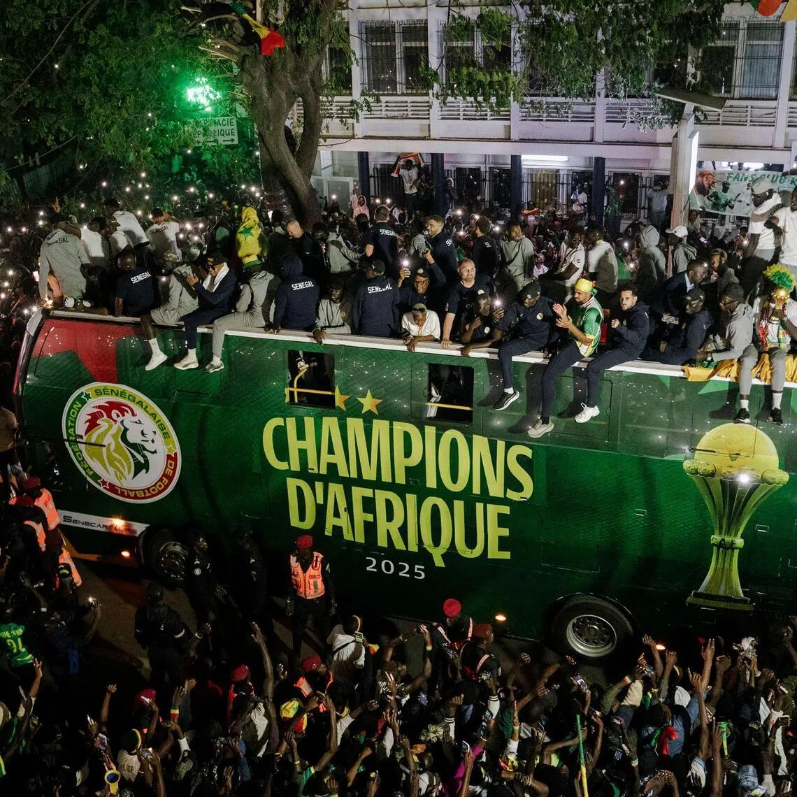 Senegal's national football team celebrate winning the Africa Cup of Nations atop an open bus during a trophy parade in the streets of Dakar on Jan 20, 2026.