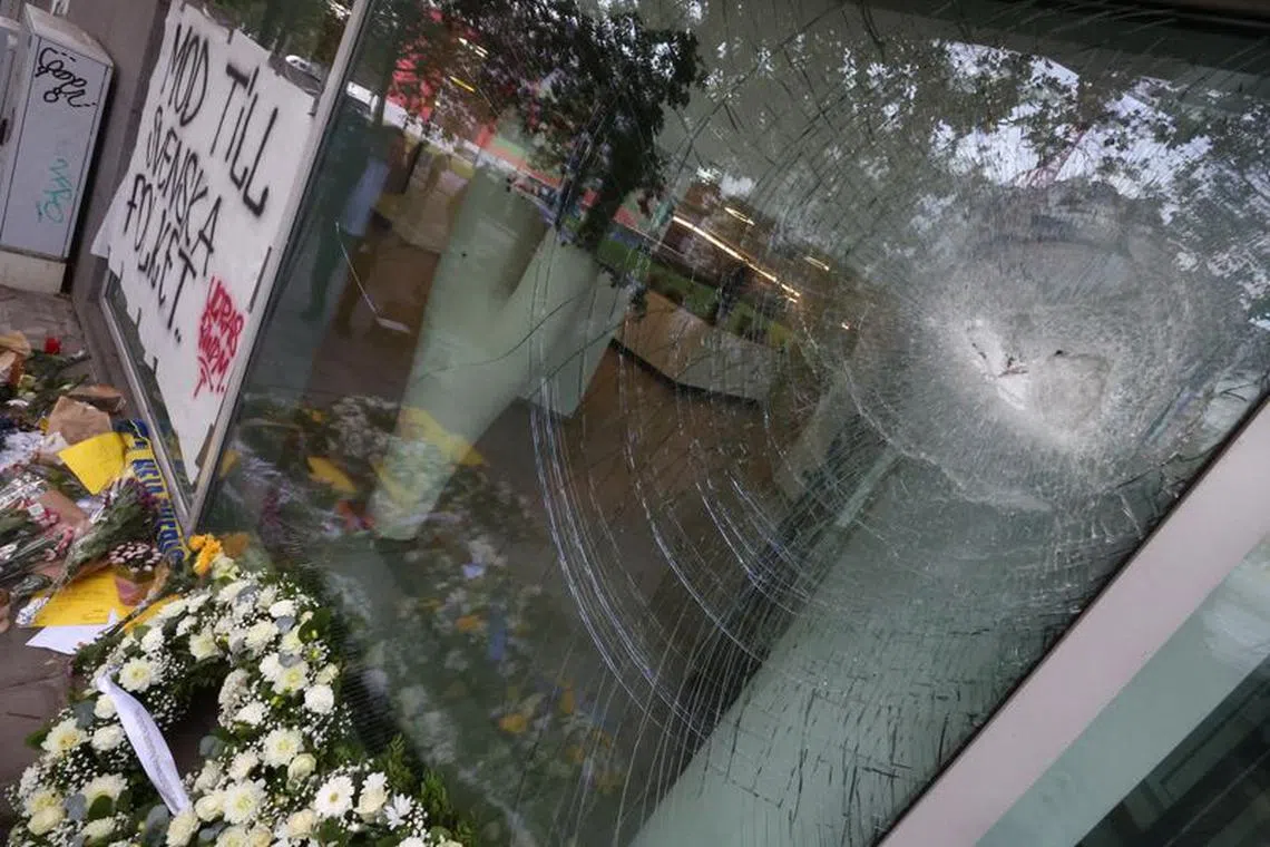 Flower wreaths placed by Swedish Prime Minister Ulf Kristersson and Belgian Prime Minister Alexander De Croo are seen underneath a damaged window, among flowers and other items left as a tribute to the victims two days after a gunman shot dead two Swedes, at the place of the shooting in Brussels, Belgium October 18, 2023. REUTERS/Yves Herman