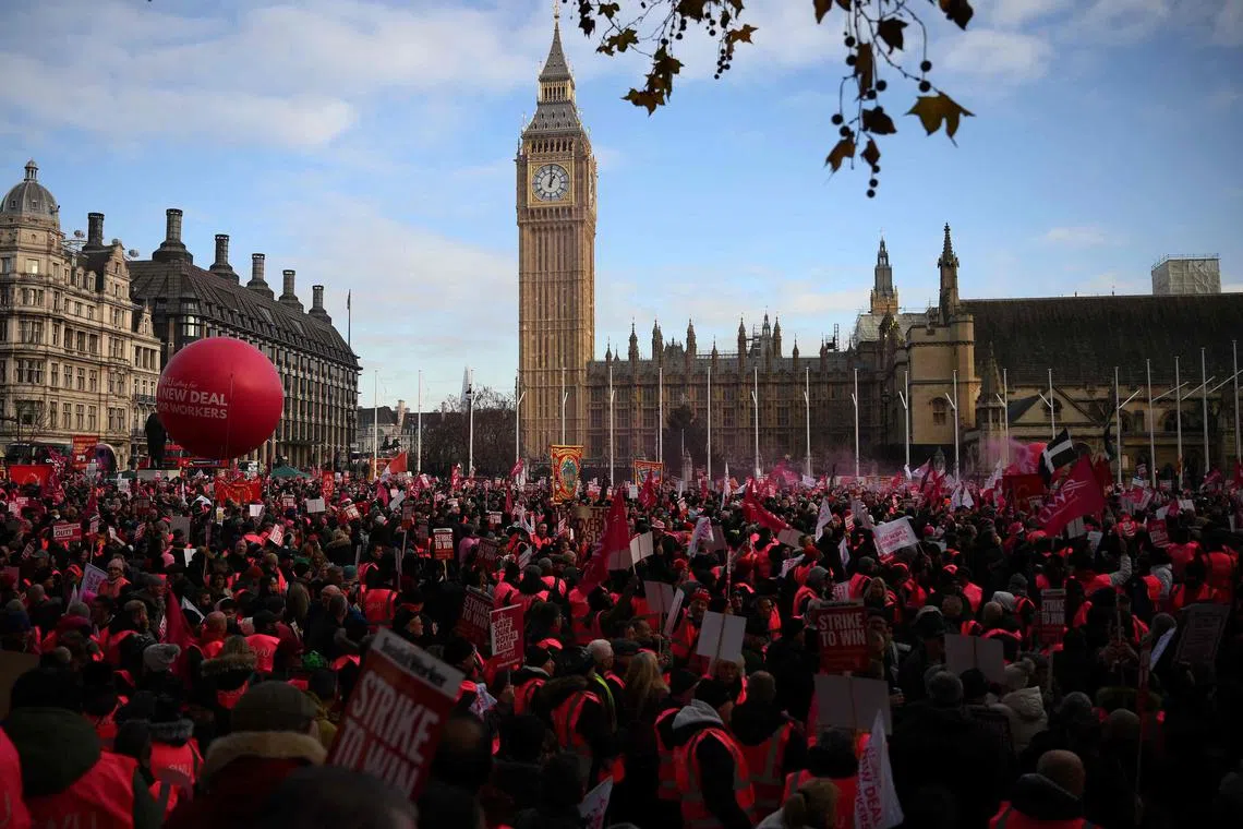 People take part in a rally organised by the Communication Workers Union (CWU), in support of Royal Mail postal workers who are on strike, in Parliament Square in central London on December 9, 2022. - The Communication Workers Union said postal workers had voted overwhelmingly for more strikes this year and next, affecting deliveries in the run-up to Christmas and opening hours at post offices. Formerly state-owned Royal Mail recently announced it would axe up to 10,000 jobs, blaming the move partly on staff strikes that contributed to a first-half loss. (Photo by Daniel LEAL / AFP)