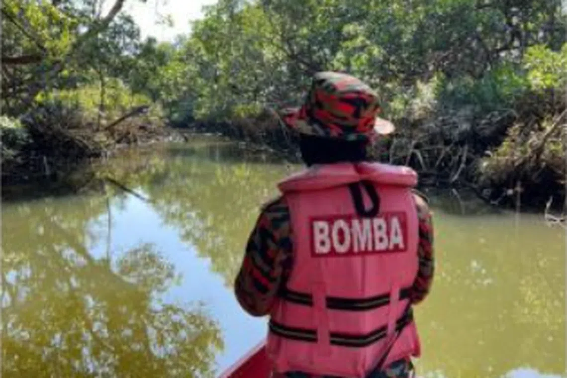 A fireman checking the river in Tawau for a man who went missing after a crocodile attack.
