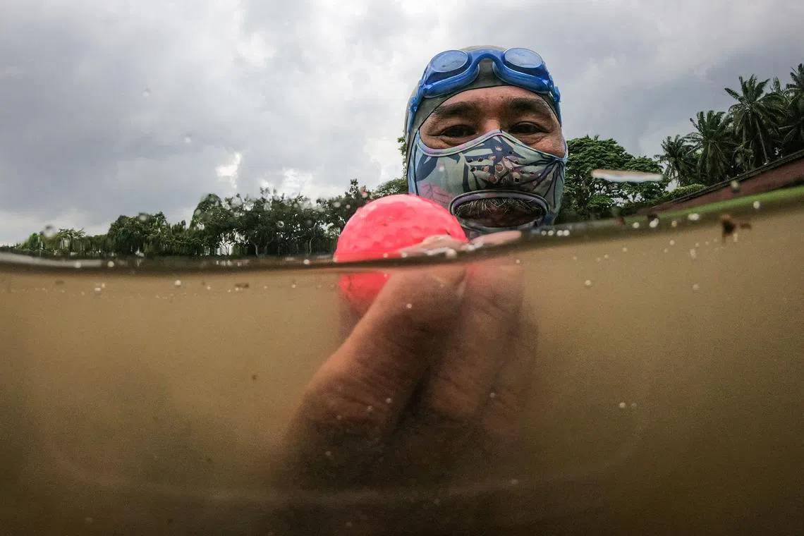 In this picture taken on November 11, 2024, Sumadi Ibrahim, 51, shows a golf ball he found inside a pond at a course in Shah Alam, on the outskirts of Kuala Lumpur. After two decades plunging Malaysian seas to defend his country, navy frogman Sumadi Ibrahim has retired to the golf course -- diving water hazards to retrieve mis-hit balls to make a living. For 22 years Sumadi served in the Royal Malaysian Navy, deployed aboard ships patrolling the shark-riddled waters off the Pacific archipelago. (Photo by Mohd RASFAN / AFP) / To go with MALAYSIA-GOLF-ENVIRONMENT-DIVING, FOCUS by Isabelle LEONG