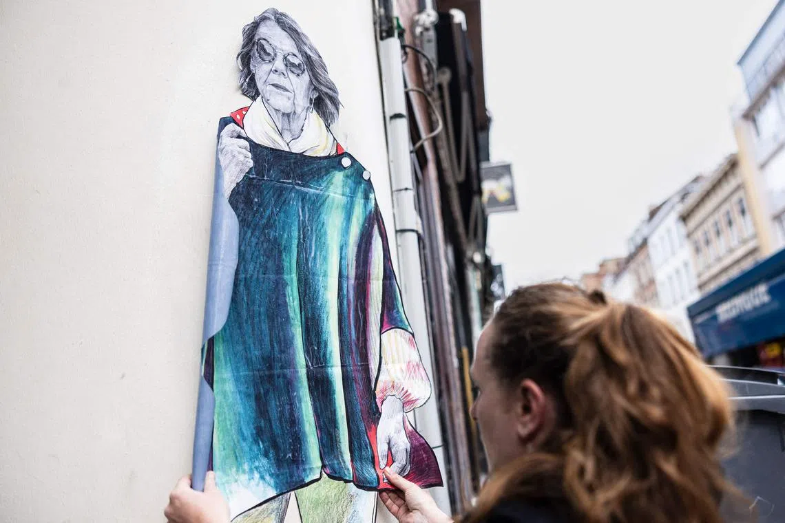 Street artist known as 'La Dame Quicolle' sticks a collage-mural representing Gisele Pelicot, the victim of numerous rapes, in Lille, northern France.