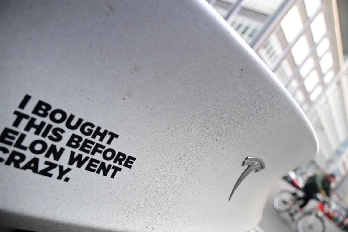 A sticker reading "I bought this before Elon went crazy" is pictured on a Tesla electric car at a charging station in Berlin, Germany.