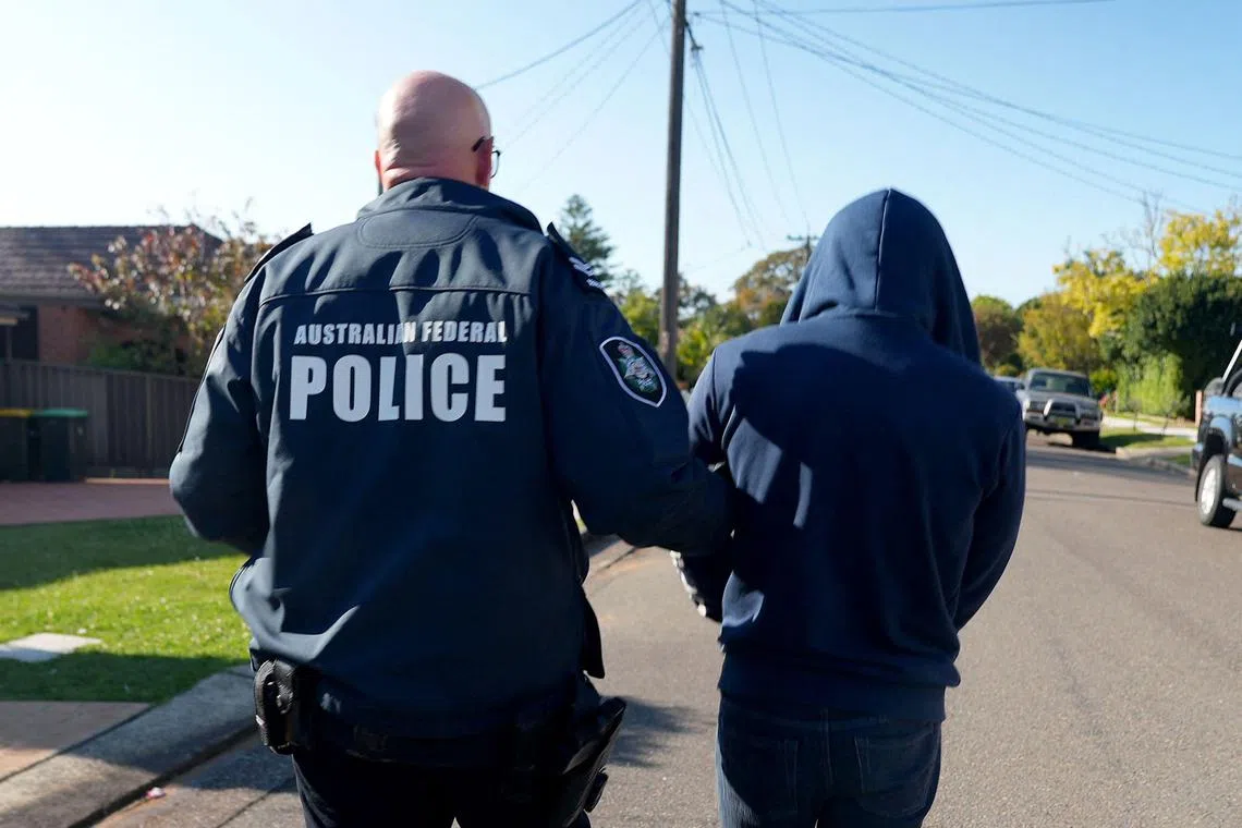 An Australian Federal Police officer arresting a suspect allegedly involved in an encrypted messaging app used by criminals worldwide.