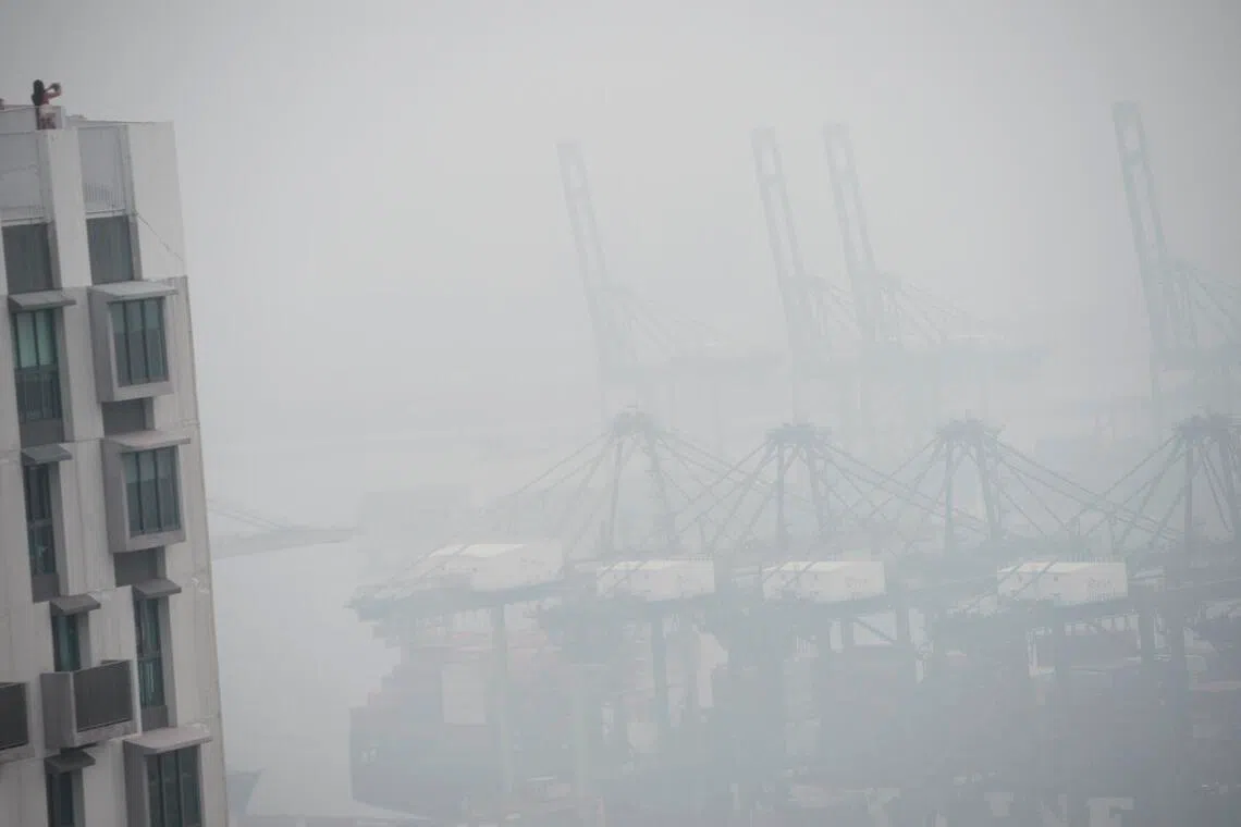 The haze provided its own filter as a woman takes a picture of the PSA from the viewing deck on the 50th floor of The Pinnacle@Duxton at around 6pm on Oct 18, 2015.