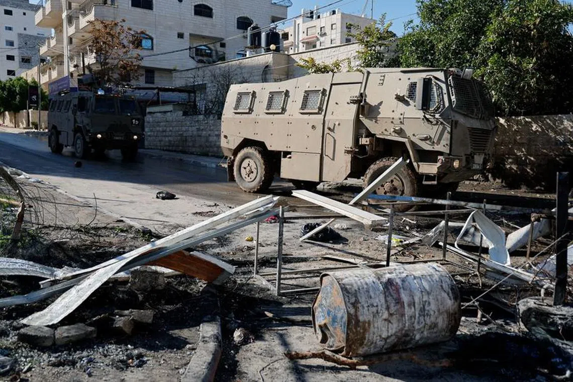 Israeli military vehicles pass by during a raid, amid the ongoing conflict between Israel and the Palestinian Islamist group Hamas, in Jenin, in the Israeli-occupied West Bank December 14, 2023. REUTERS/Raneen Sawafta