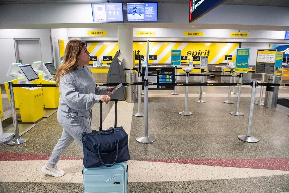 A passenger makes her way near an empty bag drop and customer service counters for Spirit airlines at Logan Airport in Boston.
