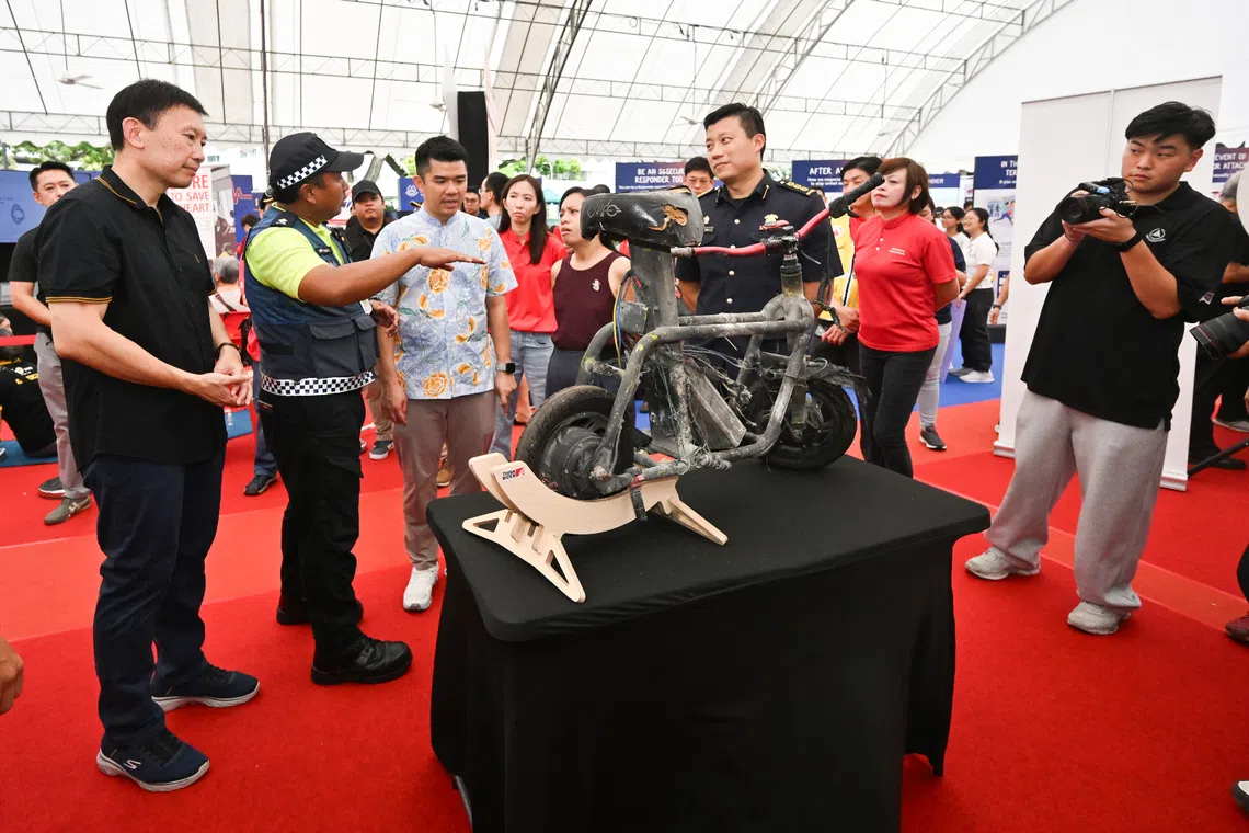 National Development Minister Chee Hong Tat (left) and his fellow Bishan-Toa Payoh GRC MPs, Mr Cai Yinzhou (third from left) and Ms Elysa Chen (fourth from left), viewing a burnt PMD at a Community Resilience Day event on Oct 19.