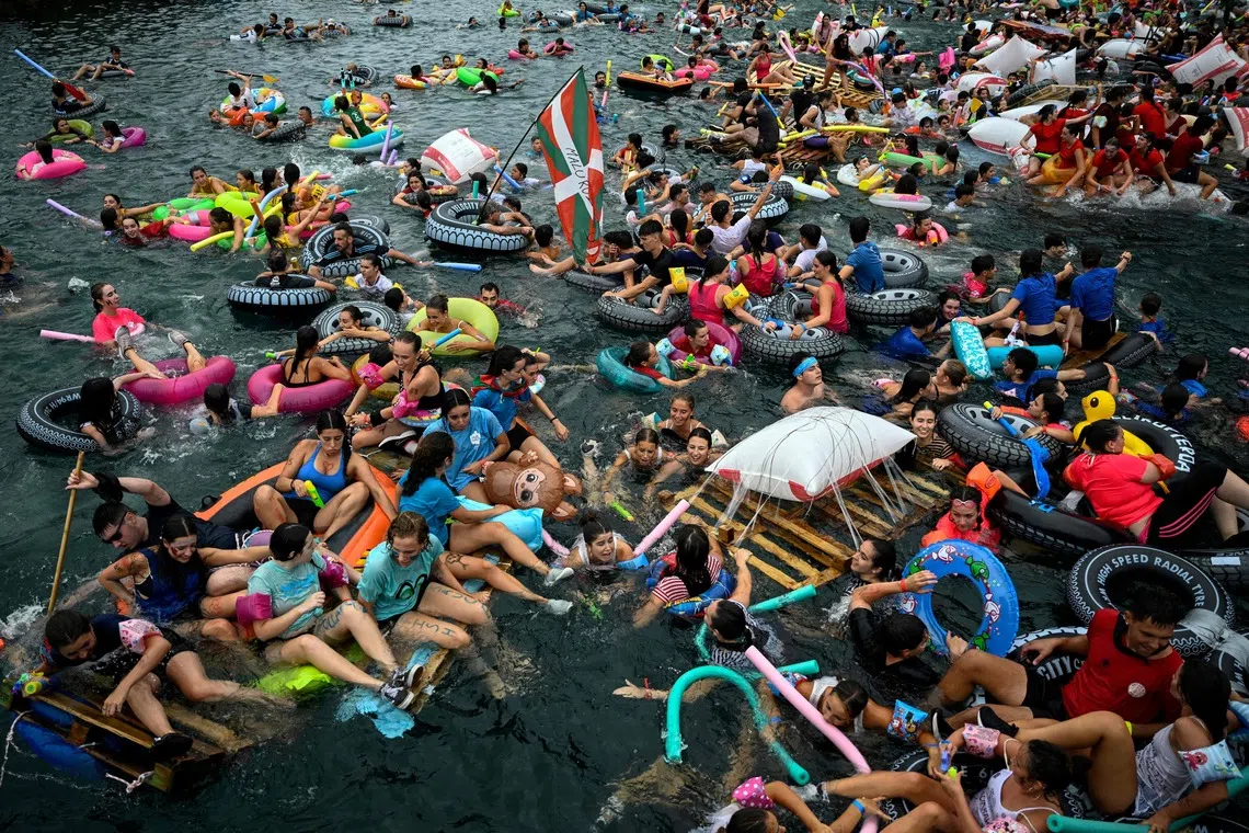 TOPSHOT - Revellers set sail on makeshift rafts and floats from the harbor towards La Concha Bay beach during the "Pirata Abordaia" (Pirate boarding) festive event in the northern Spanish Basque city of San Sebastian, on August 10, 2026. (Photo by ANDER GILLENEA / AFP)