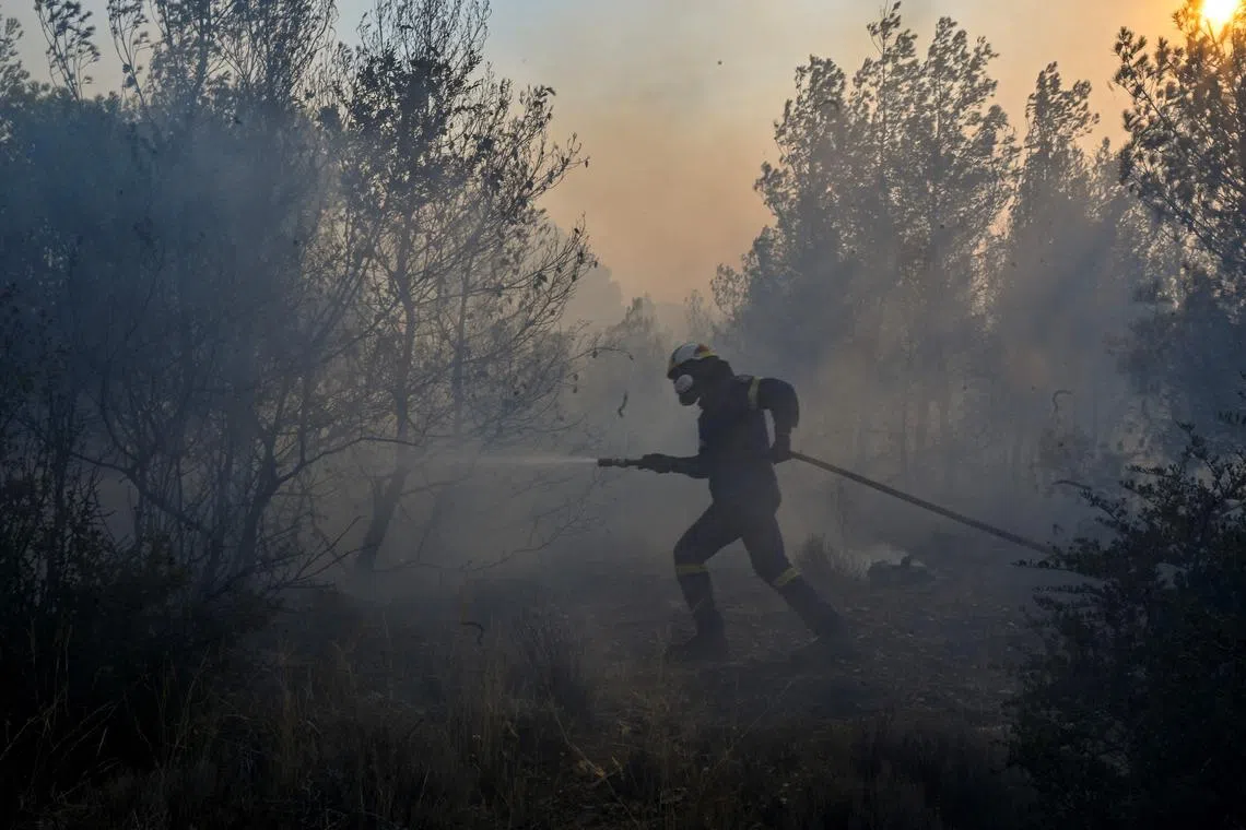 A firefighter tries to control a fire in the settlement of Neoi Pontioi, near Athens, on July 19, 2023. Extreme heat was forecast across the globe on July 19, 2023, as wildfires raged and health warnings were in place in parts of Asia, Europe and North America. Firefighters battled blazes in parts of Greece and the Canary Islands, while Spain issued heat alerts and some children in Italy's Sardinia were told to stay away from sports. (Photo by Louisa GOULIAMAKI / AFP)