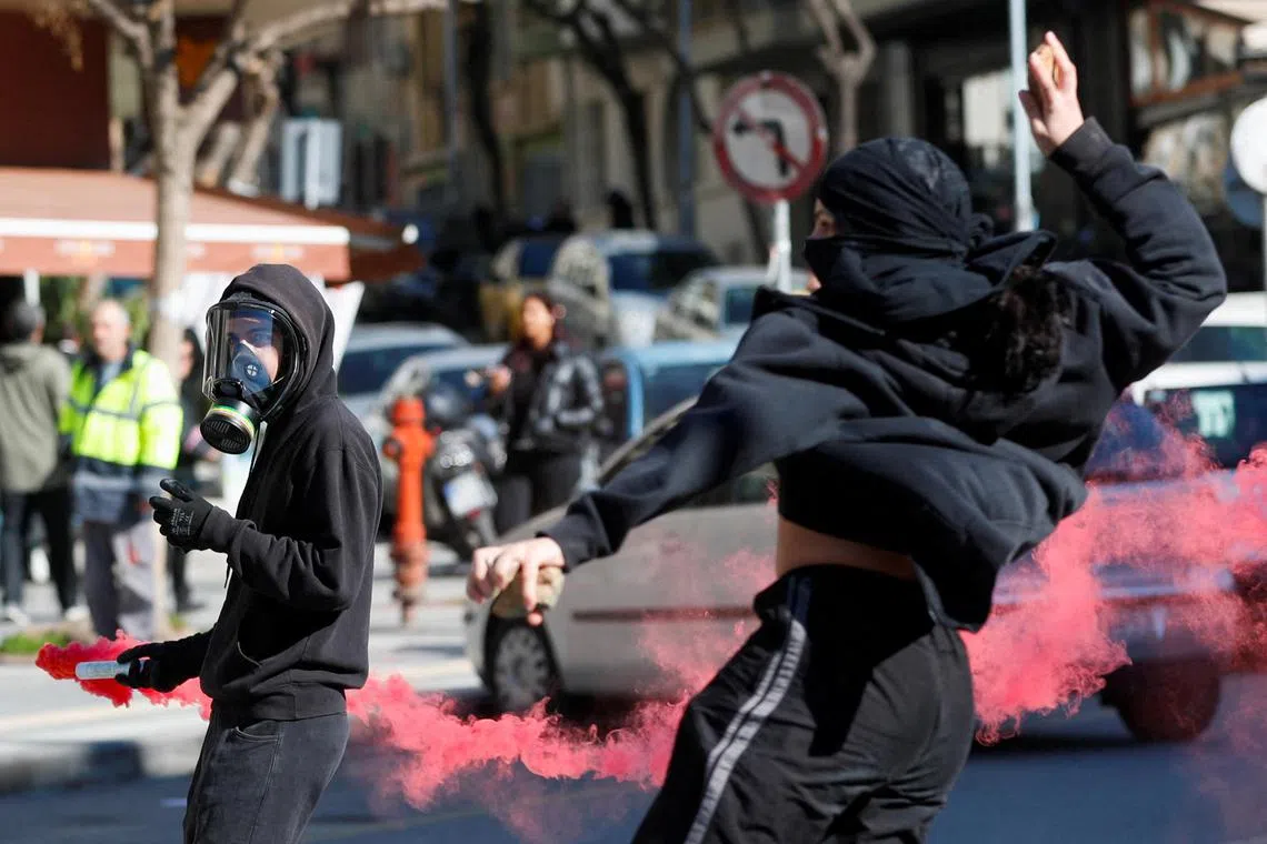 A protester holds a flare during a demonstration outside the Ministry of Macedonia and Thrace, in Thessaloniki, Greece, on March 8, 2023. 