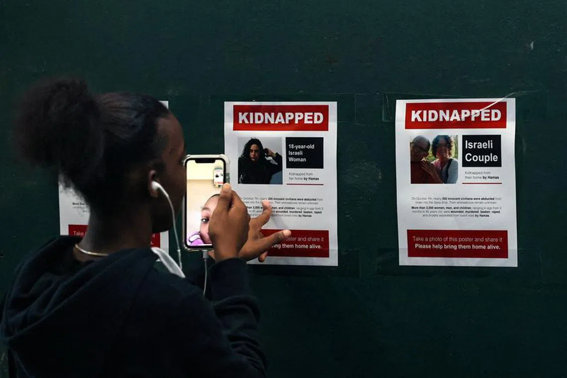 A girl records video of flyers in Times Square, of Israeli people reported missing as the city reacts to the ongoing conflict between Israel and the Palestinian militant group Hamas, in New York City, U.S., October 12, 2023. REUTERS/Brendan McDermid