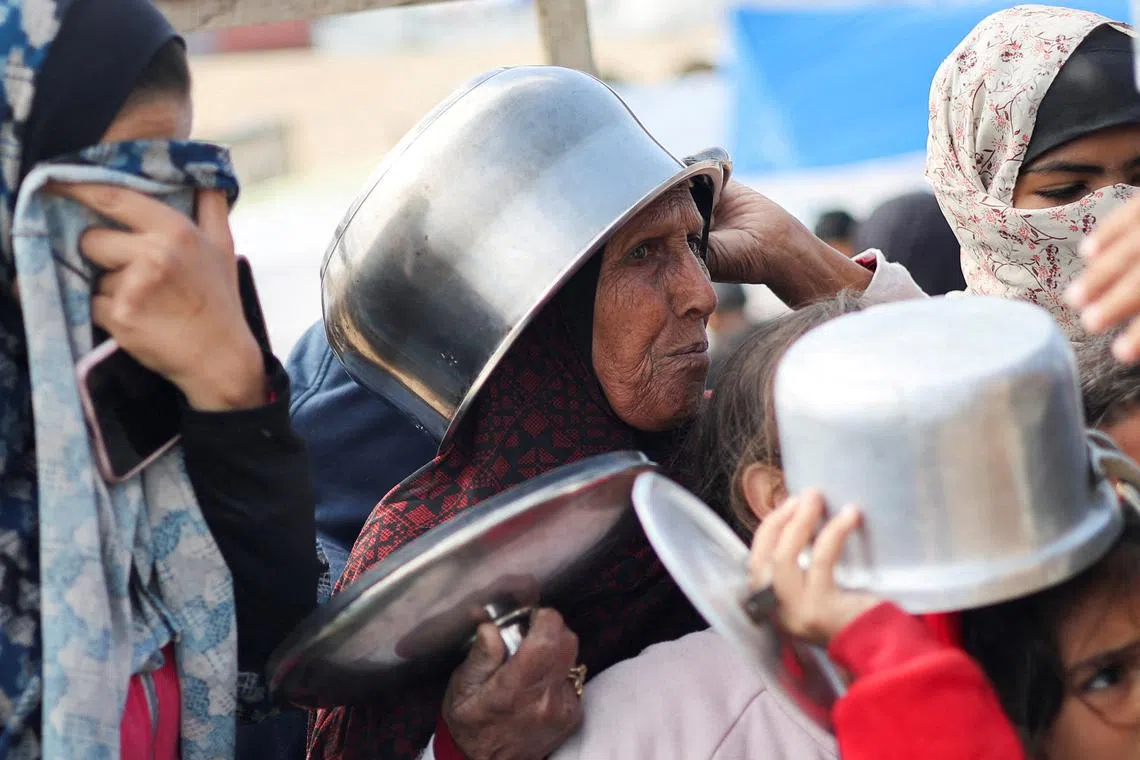 Displaced Palestinians wait to receive free food at a tent camp, amid food shortages, as the conflict between Israel and Hamas continues, in Rafah in the southern Gaza Strip, February 27, 2024. REUTERS/Ibraheem Abu Mustafa